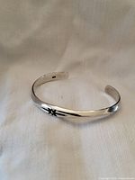 Full view of silver cuff bracelet showing overall shape and star detail.