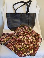 Full view of black Vince Camuto handbag beside the foldable floral patterned bag.