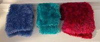 Three folded fuzzy scarves in pink-purple, teal green and lavender-blue