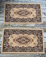 Pair of matching beige and brown floral rugs laid flat