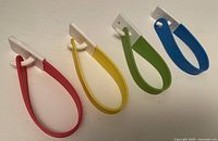 Four rubber loop hooks in red, yellow, green, blue, displayed side by side