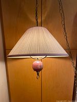 Full view of hanging ceiling lamp with pleated pink shade and chain