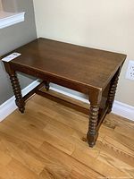 View of full side table showing rectangular wood top, turned spindle legs, and stretcher support.