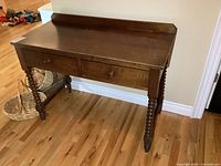 Front angle view of the antique solid wood table showing front drawers and turned legs