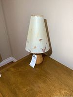 Full view of lamp showing wooden base and floral Dornbush signed shade on wooden surface.
