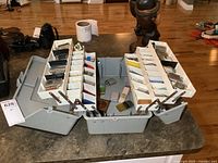 Open plastic tackle box showing three-tiered trays filled with lighters