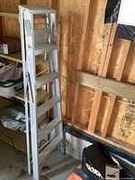 Full view of the aluminum step ladder fully folded, showing structural frame and number of steps.