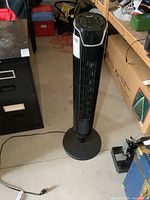 Front view of the black tower fan showing base and grille.