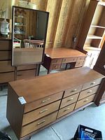 The dresser with 9 drawers and brass handles, mirror in the background, showing minor edge wear and overall condition.