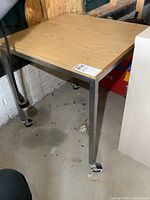 Full view of metal frame work table showing wood veneer top and caster wheels on all legs.