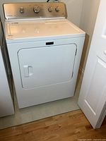 Front view of white electric dryer in laundry area.