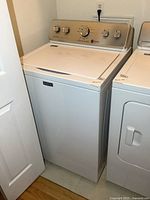 Full view of Maytag top-load washing machine positioned next to dryer in laundry space