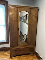 Full front view showing mirrored central door, side panels with starburst inlay, lower drawer and metal hardware