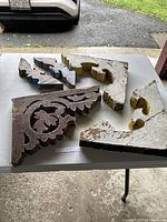 Five wooden antique corbels with different paint colors and styles showing wear and damage.