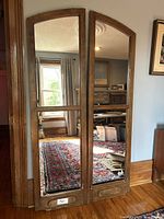 Front view of both arch-top window frame mirrors leaning against wall