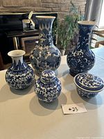 Five pieces of blue and white Chinese pottery displayed on a table, showing the various shapes and sizes in the lot.