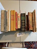 Photo showing fifteen cookbooks arranged side by side with spines readable, titles include James Beard's American Cookery, Paul Bocuse's Kitchen, and The New York Times Cookbook.