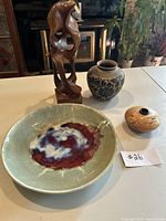 Photo of entire lot showing two wooden carvings and three pottery items on table.