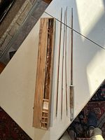 Full view showing bamboo fishing rod disassembled into four parts alongside wooden storage case on table