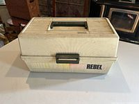 Closed exterior view of the large Rebel fishing tackle box, showing discoloration and dirt marks, with handle and latch visible.