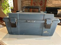 Closed blue Plano fishing tackle box with metal latches and black handle.