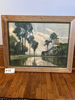 Frontal view of framed landscape artwork showing trees, water, and sky reflection.