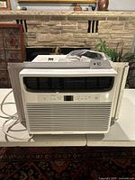 Front view of Frigidaire window air conditioner installed in removable frame with accordion side panels.