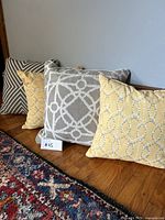 Four cushions arranged against a wooden surface showing different colors and patterns.