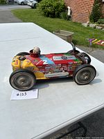 Side angle of the vintage style tin toy race car showing detailed racing decals and the driver figure.