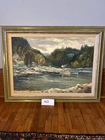 Frontal view of the framed oil painting on canvas showing a river landscape scene with forested hills and small houses.