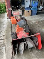 Front angled view of Toro 824 snowblower showing front auger housing, chute, and tracks with chains