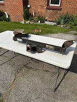 Overall view of the Hidden Hitch tow hitch receiver on a white folding table outdoors against a brick wall backdrop.