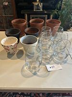 Full lot image showing seven clear glass vases, six terracotta pots (three natural, three painted black and white), and one candy cane patterned pot.