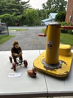 Hand-propelled monkey pull toy on wheels and a small Japanese tin duck toy on a table outdoors