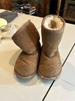 Front view of brown suede baby UGG boots showing wear and shearling lining.