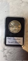 Top side of the coin showing the reverse design with a canoe and inscriptions 'CANADA', '1965', and 'DOLLAR'.