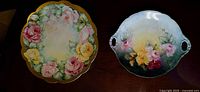 Top view of two Limoges porcelain trays with floral hand-painted designs placed on dark wood surface.