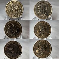 Three US $1 coins including James Buchanan Presidential Dollar, American Innovation Dollar, and Sacagawea Dollar, shown on clear plastic stands.
