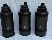 Three black TAL branded insulated thermoses side-by-side from the front showing logo and cylindrical shape.