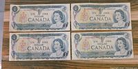 Front sides of four circulated 1973 Canadian one dollar bills arranged in two rows, showing portrait of Queen Elizabeth II and serial numbers.