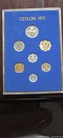Frontal photo of cased 1971 Ceylon Proof Coin Set with seven coins mounted on blue background under glass