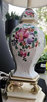 Close-up of white porcelain lamp base with detailed floral hand-painted decoration and embossed pattern