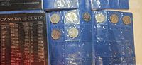 Photo of Canadian 50 cents coins in blue coin book with informational page about Canada 50 cents.