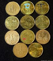 Top-down photo showing 10 Canadian one-dollar commemorative coins featuring various designs including wildlife, historical events, and cultural themes, some with colored details.