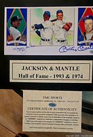 Close-up photo of the framed display showing Mickey Mantle and Reggie Jackson trading cards and action photograph along with their blue ink autographs and a plaque stating Hall of Fame induction years.