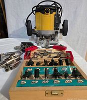 Front view of yellow plunge router on white background with wooden bit case in foreground