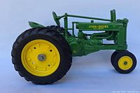 Side view of the John Deere The Model Diesel die-cast 1:16 scale tractor model with yellow wheels and green body.