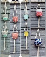 Front view of all five macrame plant hangers with pots against a gray brick wall, showing three double hangers and two singles