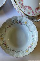 Close-up of scalloped bowl with floral garland and gold trim