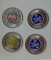 Four Canadian $2 Toonie coins, two with commemorative colored designs and two standard.